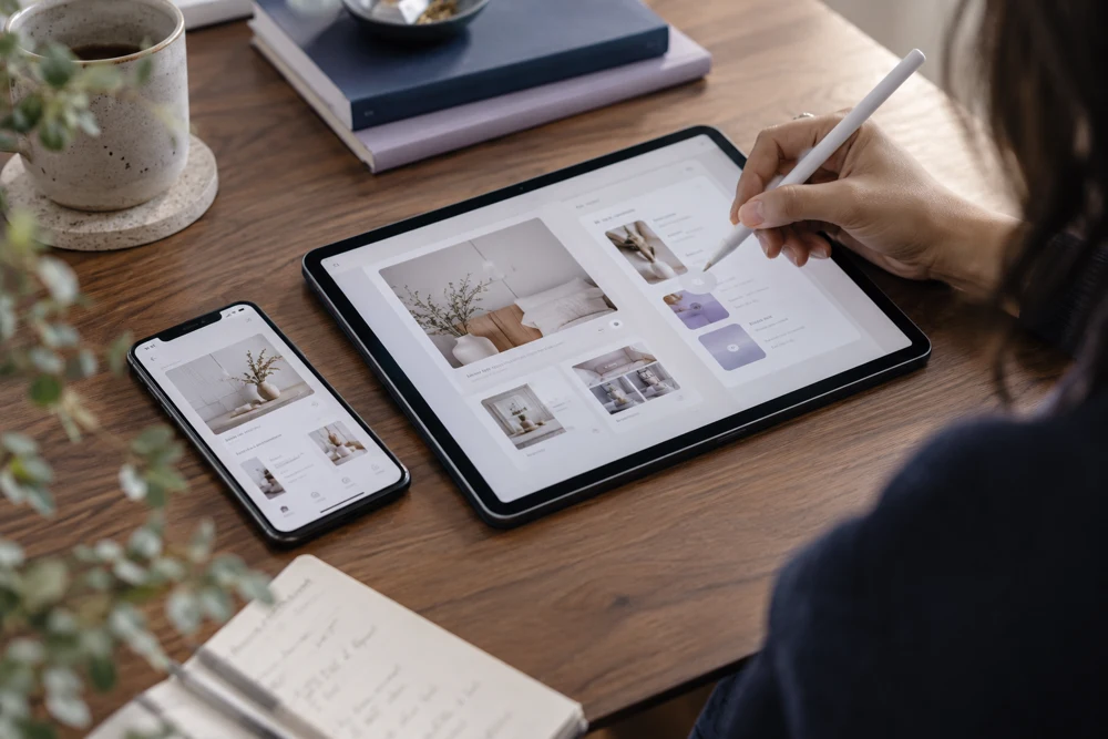 Designer refining an interface on a tablet beside a smartphone